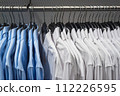 Blue and white shirts on hangers hanging on the rack 112226595