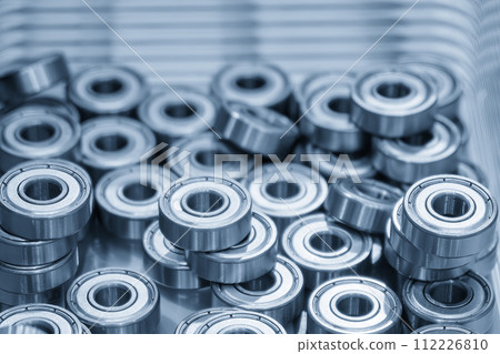 Close up scene the pile of cylindrical ball bearing parts in the light blue scene. 112226810