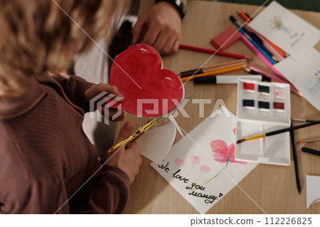 Boy cutting out red paper heart Boy cutting out red paper heart 112226825
