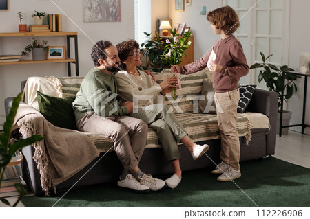 Son passing bunch of flowers to mother 112226906