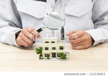 Hand observing a house model with a magnifying glass 112226921