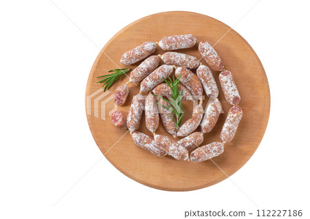 Mini salami on a wooden cutting board isolated, top view. Mini salami on a wooden cutting board isolated, top view. 112227186