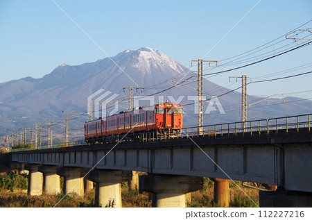 Rear view of the Kiha 40 series Kiha 47 type local train (3-car train) passing the Hino River railway bridge with Mt. Daisen in the background 112227216