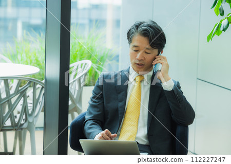 Businessman talking on smartphone in office 112227247