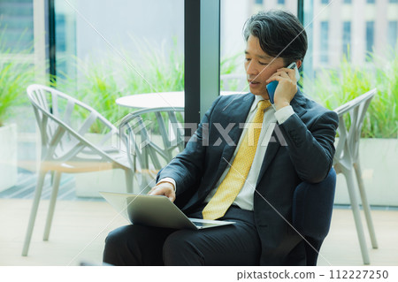 Businessman talking on smartphone in office 112227250