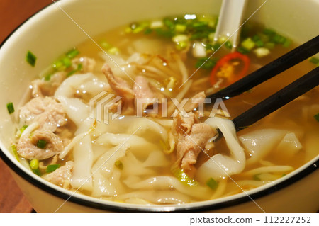 A close-up of a Vietnamese pho soup with chopsticks. 112227252