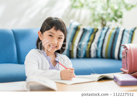 An elementary school girl doing homework in the living room. 112227552