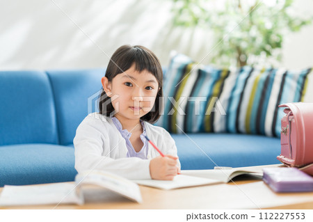 An elementary school girl doing homework in the living room. An elementary school girl doing homework in the living room. 112227553