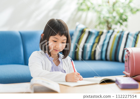An elementary school girl doing homework in the living room. An elementary school girl doing homework in the living room. 112227554