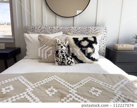 This inviting bedroom showcases a beautiful blend of warm neutrals and rich textures, highlighted by a striking circular mirror above a sleek, dark wood desk. The room is accented with a plush This inviting bedroom showcases a beautiful blend of warm neutrals and rich textures, highlighted by a striking circular mirror above a sleek, dark wood desk. The room is accented with a plush 112227874