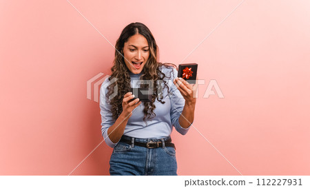 Woman opening a gift box and getting surprised Woman opening a gift box and getting surprised 112227931