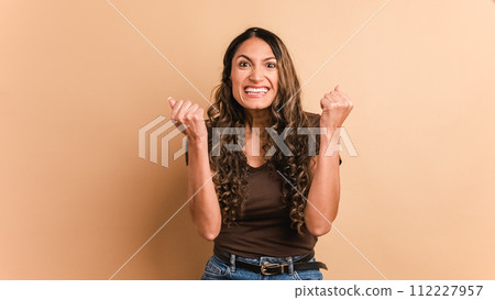 Happy hispanic woman celebrating raising fists and looking at camera 112227957