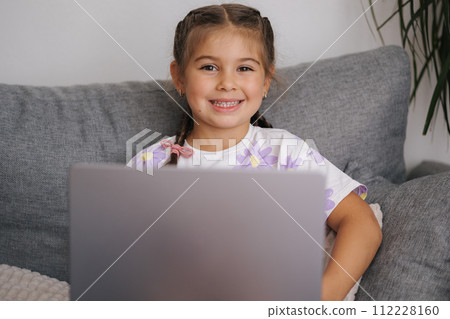Portrait of beautiful little girl using smart devise. Five year old girl open and use laptop 112228160