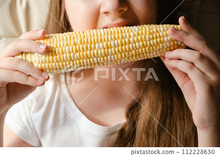 Portrait of adorable cute child girl biting big vegetable corn 112228630