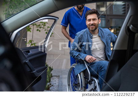 Disabled man getting on a car, male nurse helping him 112229237