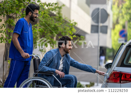 Man on a wheelchair getting into a car Man on a wheelchair getting into a car 112229250