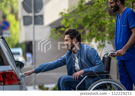 Man on a wheelchair getting into a car Man on a wheelchair getting into a car 112229251