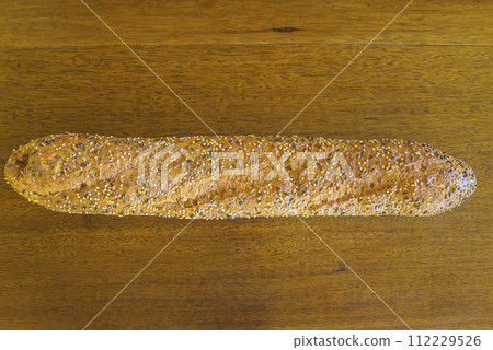 One traditional french baguette on a vintage wooden background One traditional french baguette on a vintage wooden background 112229526