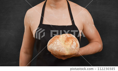 Male chef with bread in his hand on a black background. Cooking concept 112230385