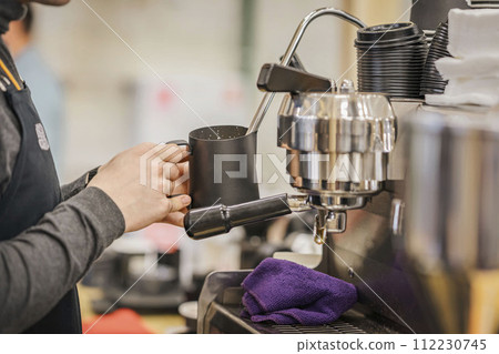 Professional barista working in bar whipping milk into foam for cappuccino coffee Professional barista working in bar whipping milk into foam for cappuccino coffee 112230745