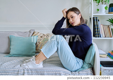 Young sad unhappy woman sitting on couch at home 112230945