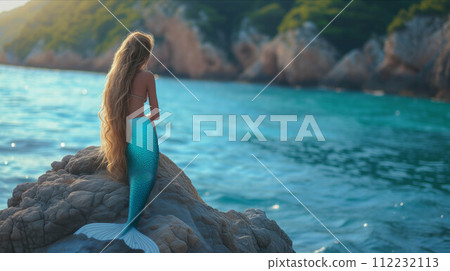 Young mermaid sitting on a rock on an island in the sea. 112232113