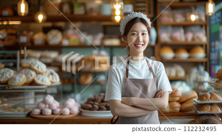 Asian woman wearing an apron with arms crossed inside a bakery shop. 112232495