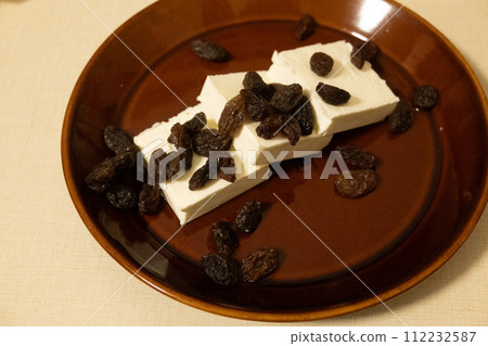 A snack made with sliced cream cheese sprinkled with rum raisins 112232587