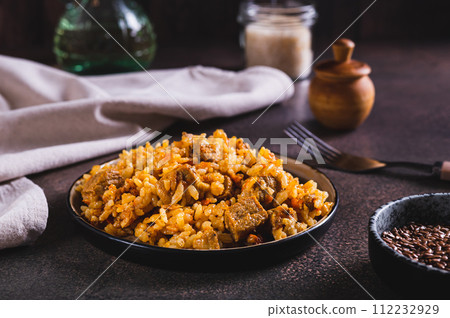Delicious Asian pilaf with meat on a plate on the table 112232929