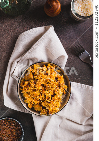 Traditional spicy pilaf with rice and meat on a plate on the table top and vertical view Traditional spicy pilaf with rice and meat on a plate on the table top and vertical view 112232940