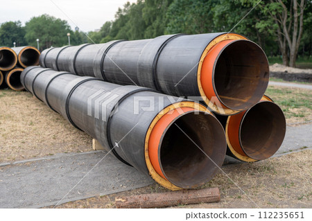 Steel pipe with heat insulation. New black insulated steel pipes at municipal construction site outdoors. Heating main district pipeline renewal or reconstruction. 112235651