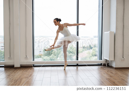Caucasian ballerina posing in bright class studio with panoramic windows 112236151