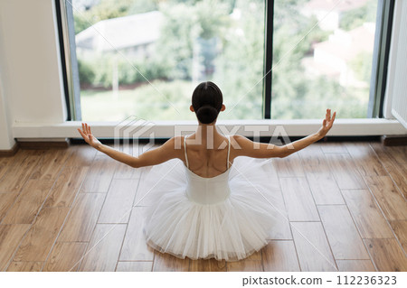 Focused young ballerina dressed in white tutu costume practice ballet poses. 112236323