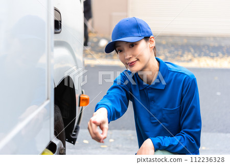 Female truck driver performing pre-operation inspection Female truck driver performing pre-operation inspection 112236328