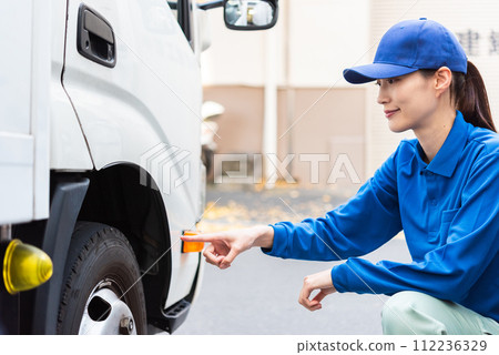 Female truck driver performing pre-operation inspection Female truck driver performing pre-operation inspection 112236329