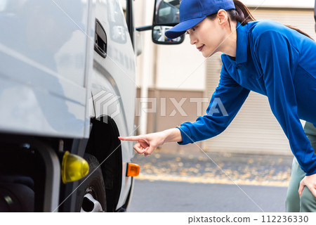 Female truck driver performing pre-operation inspection 112236330