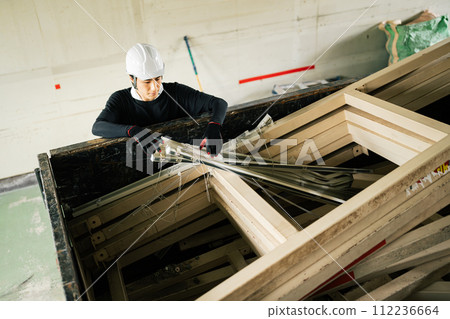 A worker throws scrap wood into a loading platform A worker throws scrap wood into a loading platform 112236664