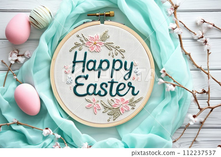 Embroidered Happy Easter message with floral embroidery and pastel eggs on turquoise fabric. Spring holiday concept for greeting card design 112237537