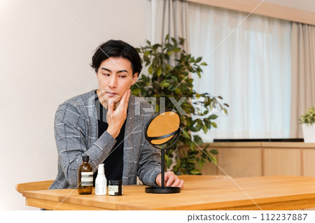 一位30多歲的男子在客廳裡使用男士化妝品護理自己的皮膚(男士美容) 一位30多歲的男子在客廳裡使用男士化妝品護理自己的皮膚(男士美容) 112237887
