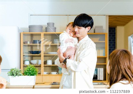 A father holding a baby at home and his family watching over him A father holding a baby at home and his family watching over him 112237889