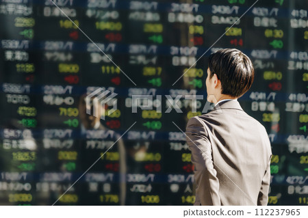 一位三十多歲的商人投資者在戶外看股票價格板的電子公告板的背影 112237965