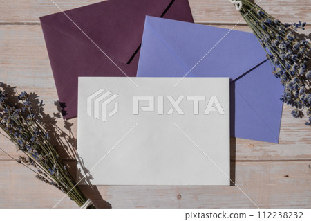 Flat lay composition of white paper greeting card on envelope with dry lavender flowers. Copy space template mock up. Top view. Concept of Wedding invitation postcard. Business advertisement 112238232
