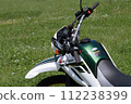 Parked off-road bike 2 receiving strong sunlight from above in a sunny midday spring meadow 112238399