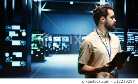 IT specialist in server room ensuring valuable data remains secure from potential threats, safeguarding against unauthorized access and vulnerabilities, securing system from DDoS attacks 112239297