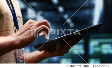 System administrator checking energy efficient supercomputers using renewable sources to minimize consumption and reduce business carbon footprint. Expert working in sustainable data center, close up 112239367