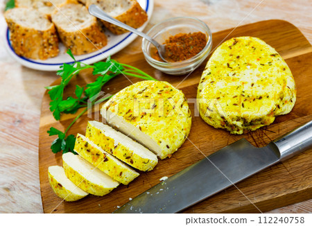 Slices of spicy roasted cottage cheese with turmeric and cumin on wooden board 112240758