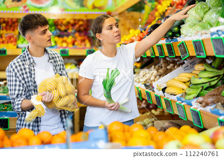 Young husband and wife choose fresh vegetables together in grocery supermarket 112240761