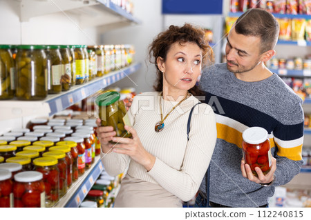 Couple man and woman choose pickled cucumbers and tomatoes Couple man and woman choose pickled cucumbers and tomatoes 112240815