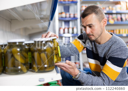 In Russian goods store, man choose jar of pickled cucumbers In Russian goods store, man choose jar of pickled cucumbers 112240860