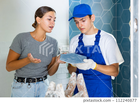 Builder discussing tiles with female owner of apartment being renovated Builder discussing tiles with female owner of apartment being renovated 112240877